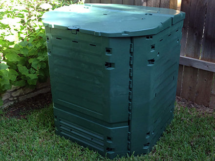 Thermo King 900 Compost Bin in green with dual hinged lids, ventilation slots, and insulated Thermolen® walls outdoors on grass near wooden fence