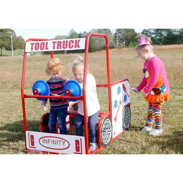 Children playing on a colorful outdoor tool truck playset with interactive panels and steering wheels in a grassy field