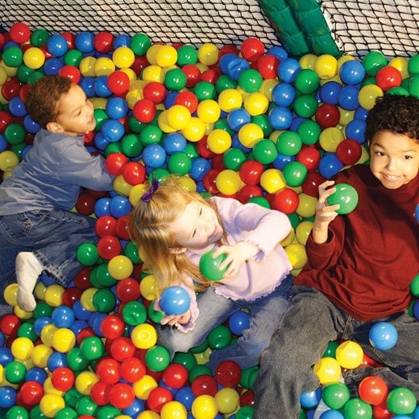 Overhead view of three children playing in a colorful indoor jungle-themed ball pit with soft flooring and protective netting