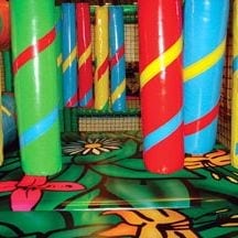 Indoor jungle-themed play area with colorful padded pillars, soft foam flooring, and playful nature-inspired patterns