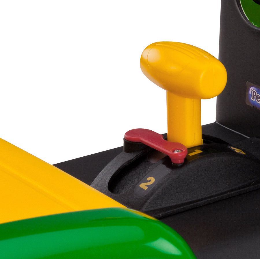 Close-up of yellow and red gear shifter on green and yellow children's ride-on tractor with working front loader controls
