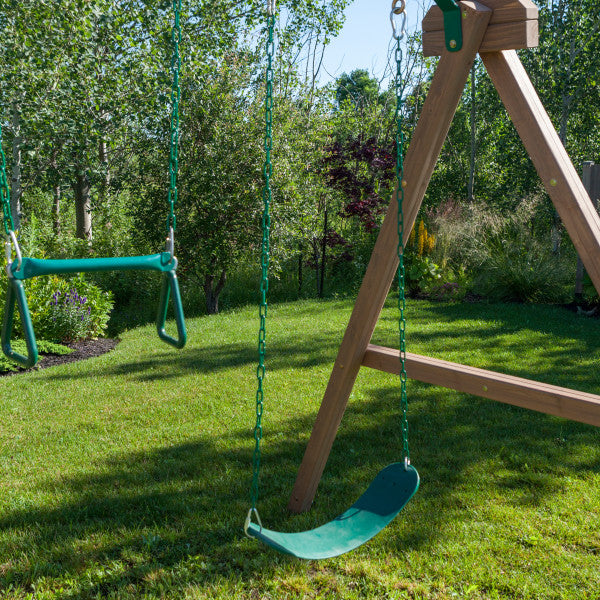 Wooden swing set with two green belt swings and an acro bar on grassy lawn surrounded by trees