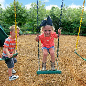 Two children standing on swings with molded foot holders and grippy coated chains in an outdoor playground