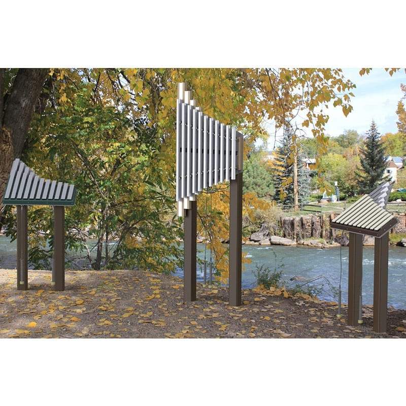 Outdoor musical park instruments with metal bars on brown poles near a river and autumn trees