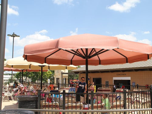 Coolbrella Single Post Umbrella shade structure in terracotta at outdoor aquatic center with seating and visitors