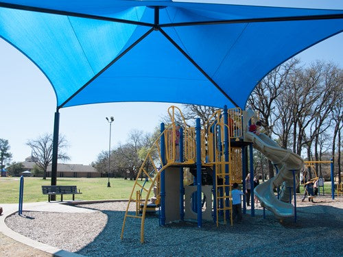 Blue conical roof shade structure with four black posts over playground slide in park setting