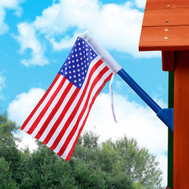 American flag on blue reinforced plastic pole mounted on wooden swing set, waving against partly cloudy sky
