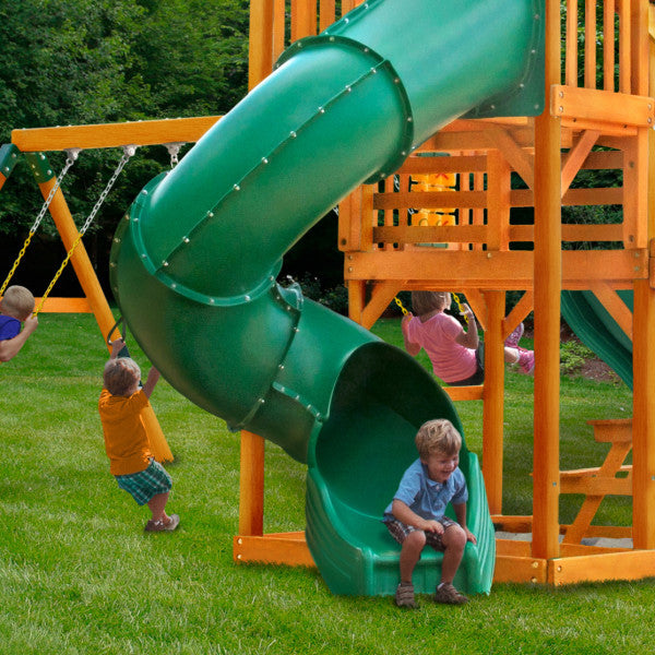 Wooden playset with green spiral slide, multiple swings, climbing rope, and children playing on grass outdoors