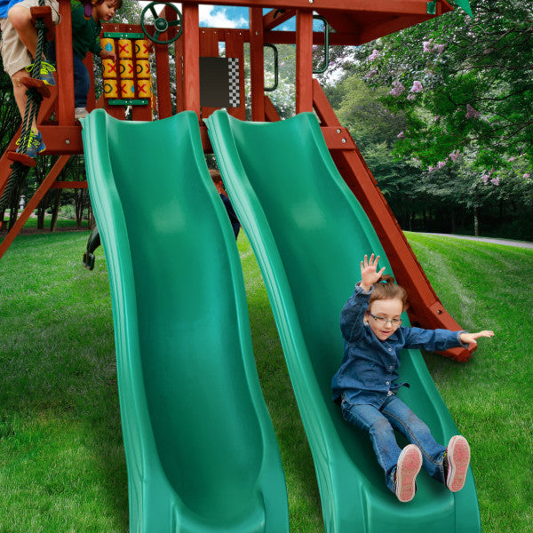 Two green Alpine Wave slides side by side on a redwood wooden swing set with children playing outdoors