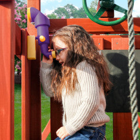 Child looking through a purple and yellow periscope mounted on wooden playset with green steering wheel and rope ladder