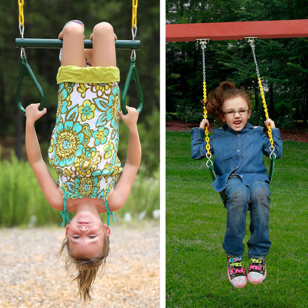 Two children on green belt swings with yellow chains attached to a redwood-finished wooden swing set outdoors on grass and wood chips