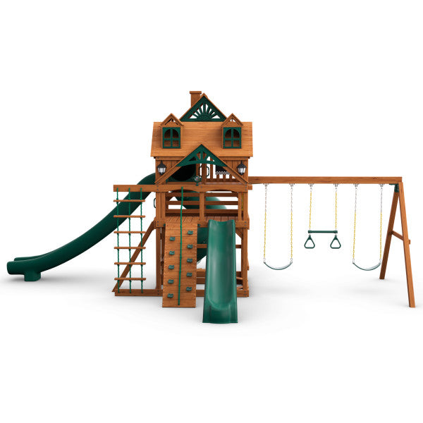 Cedar wooden playset with two green slides, rock climbing wall, rope ladder, and three swings with yellow chains