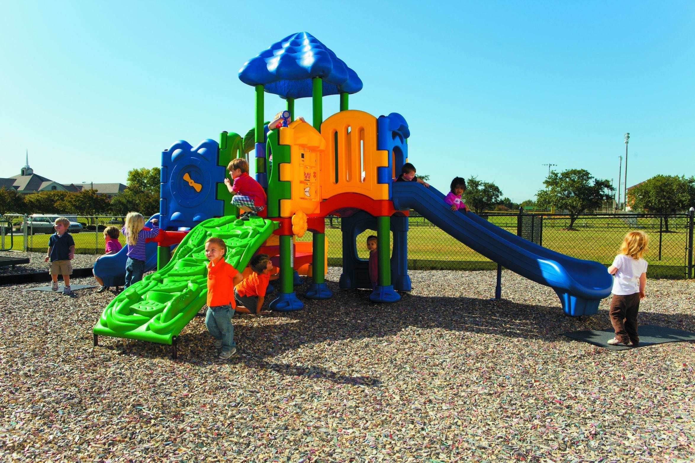 Children playing on colorful multi-level playground with slides.