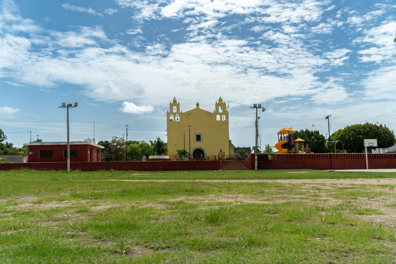 Yellow church building with playground and red wall.