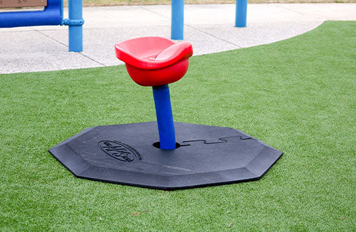 Red and blue playground swing on a green grassy area