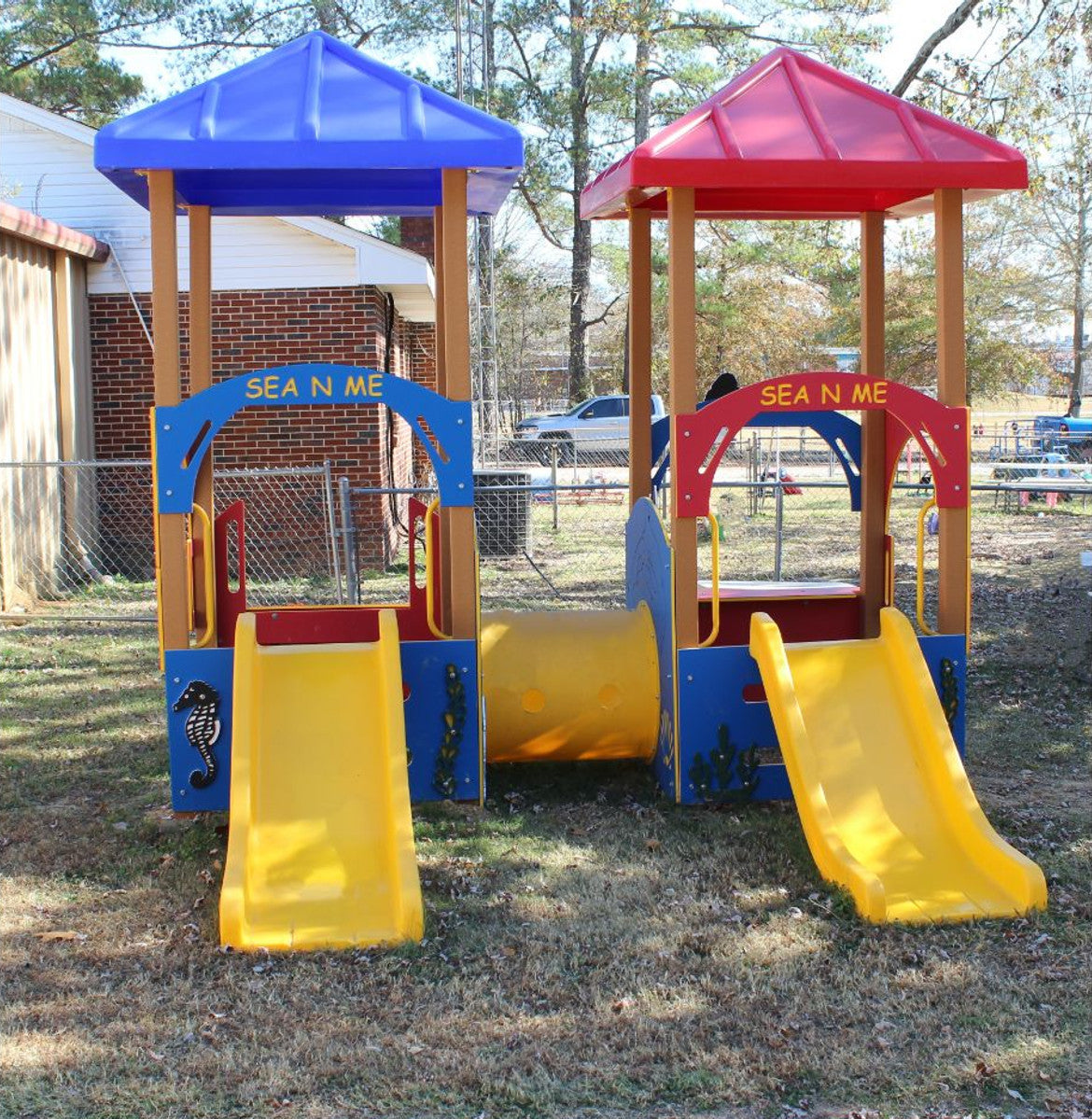 Colorful playground structure with two yellow slides on a grassy area.