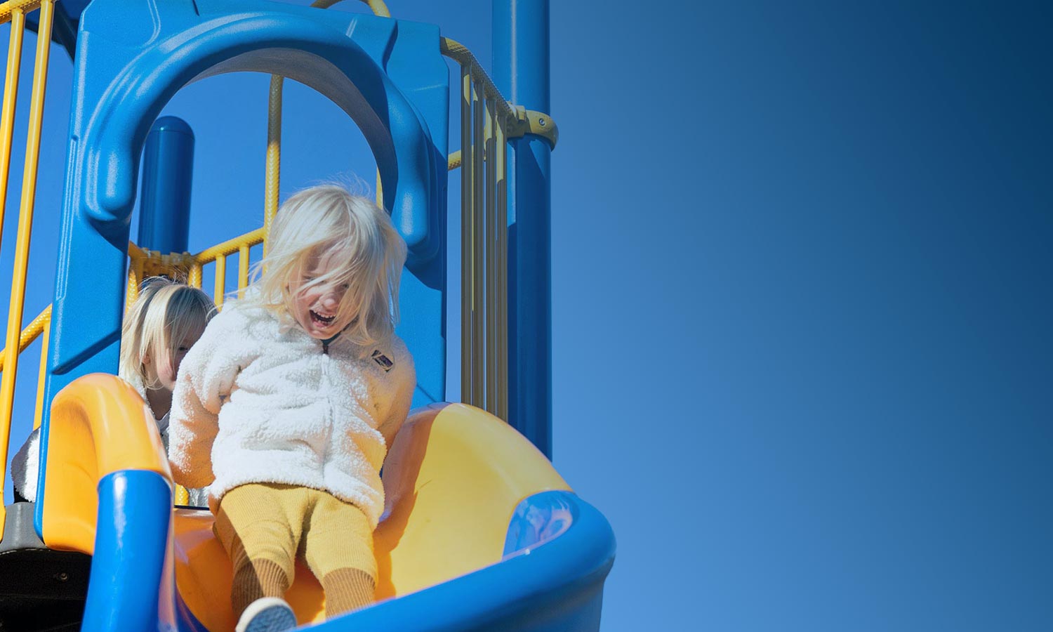 Playground Equipment. Girl Sliding down a slide at a park