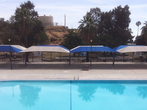 A Full Cantilever Pool Shade Structure with blue awnings and palm trees.