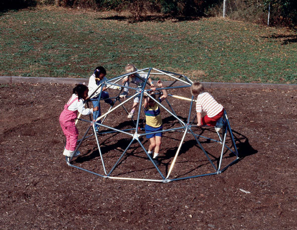 Children playing on galvanized steel geo dome climber with wood chip ground cover in outdoor playground